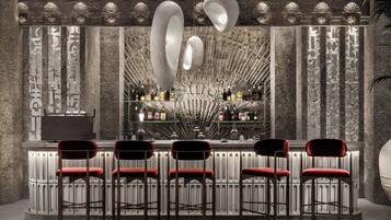 A bar area with a stone wall, bar stools, and a variety of bottles.