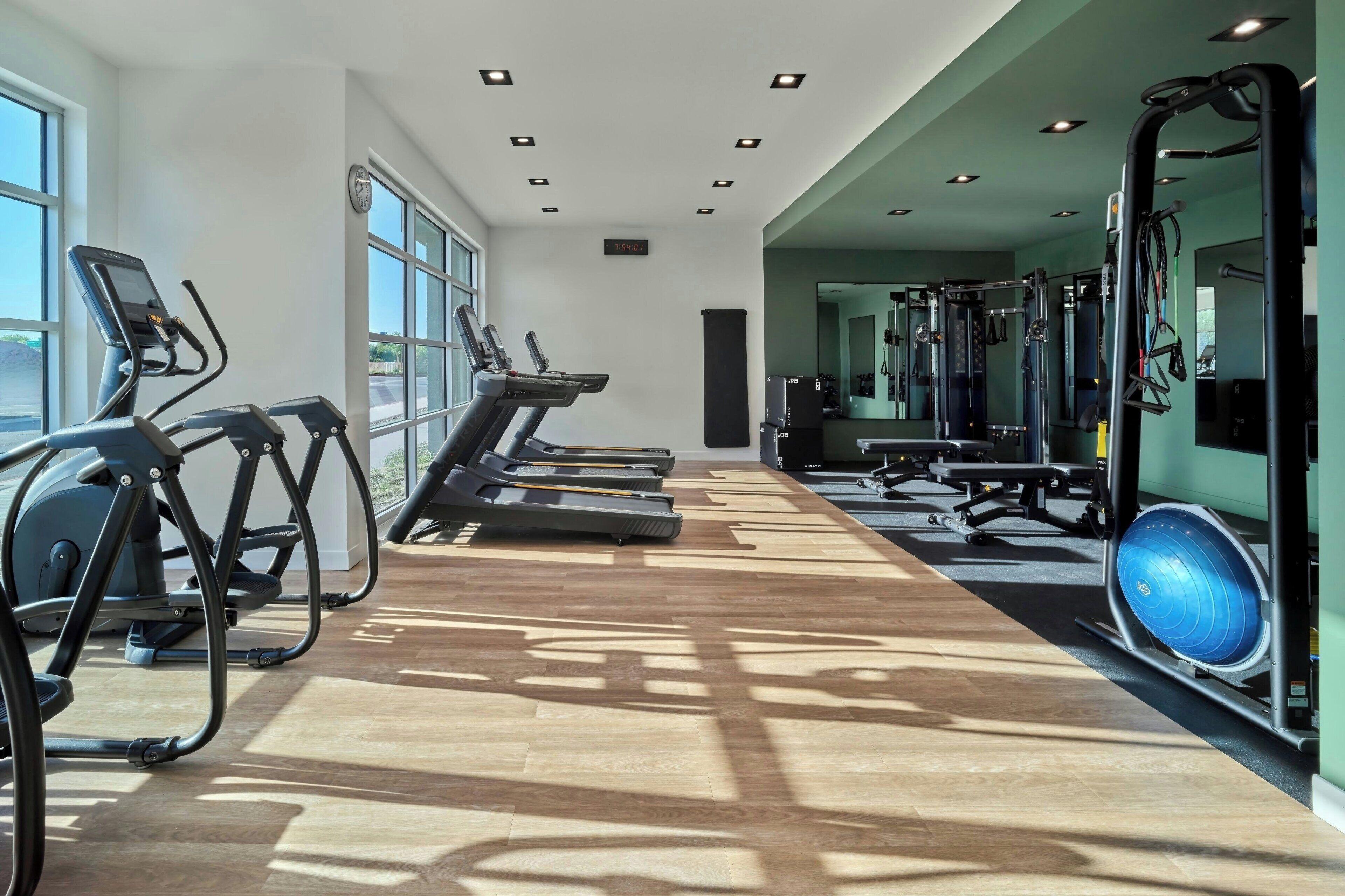 Un gimnasio con cintas de correr, pelotas de ejercicio y máquinas de pesas.