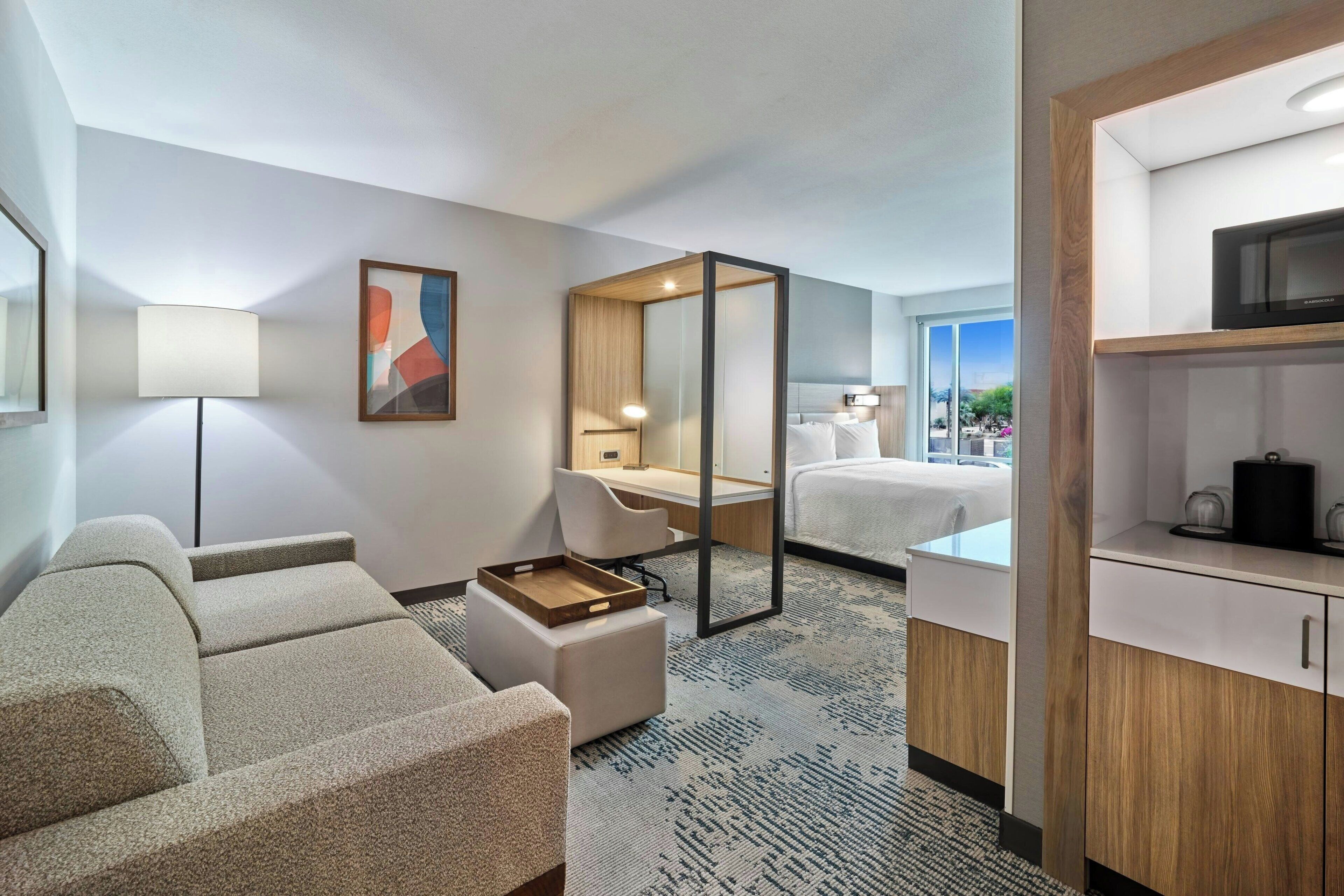 Une chambre d’hôtel équipée d’un canapé, d’un bureau, d’un lit, d’une tél évision et offrant une vue sur l’extérieur.