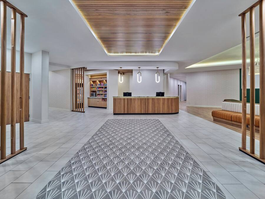 A reception area with a wooden reception desk, a patterned rug, and a seating area with a sofa.
