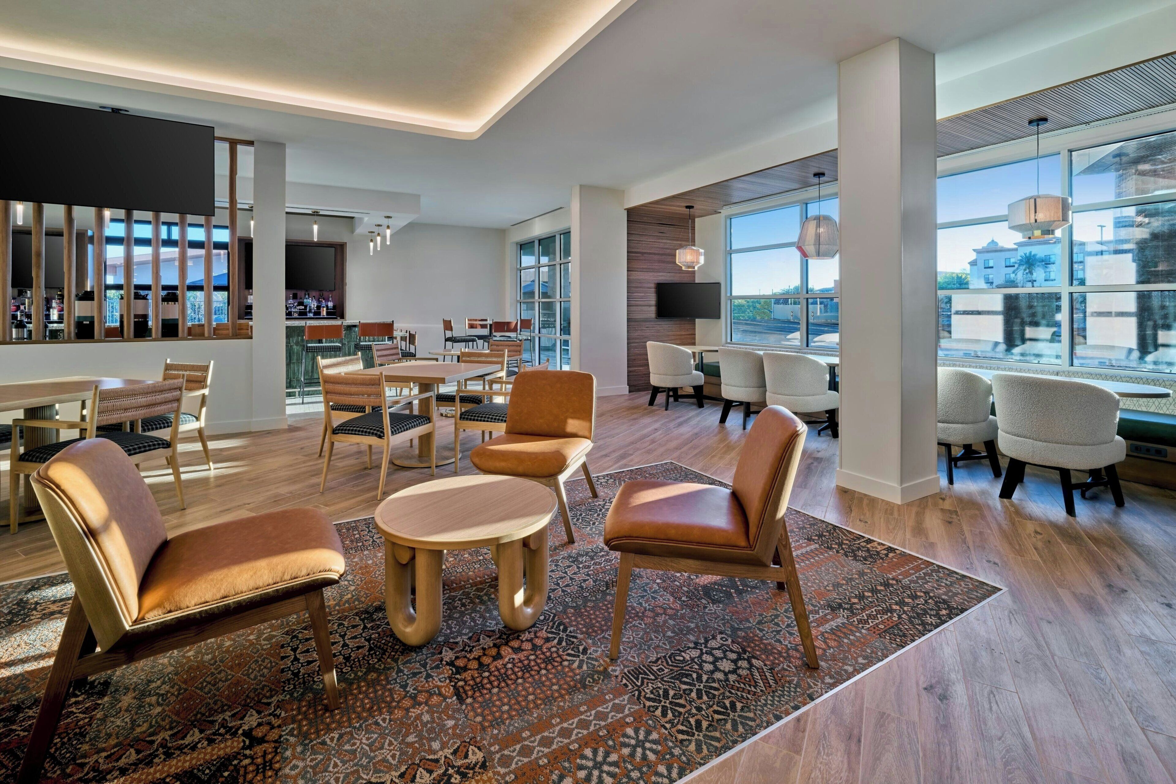 A spacious hotel lobby with a bar area, seating arrangements, and large windows offering views.