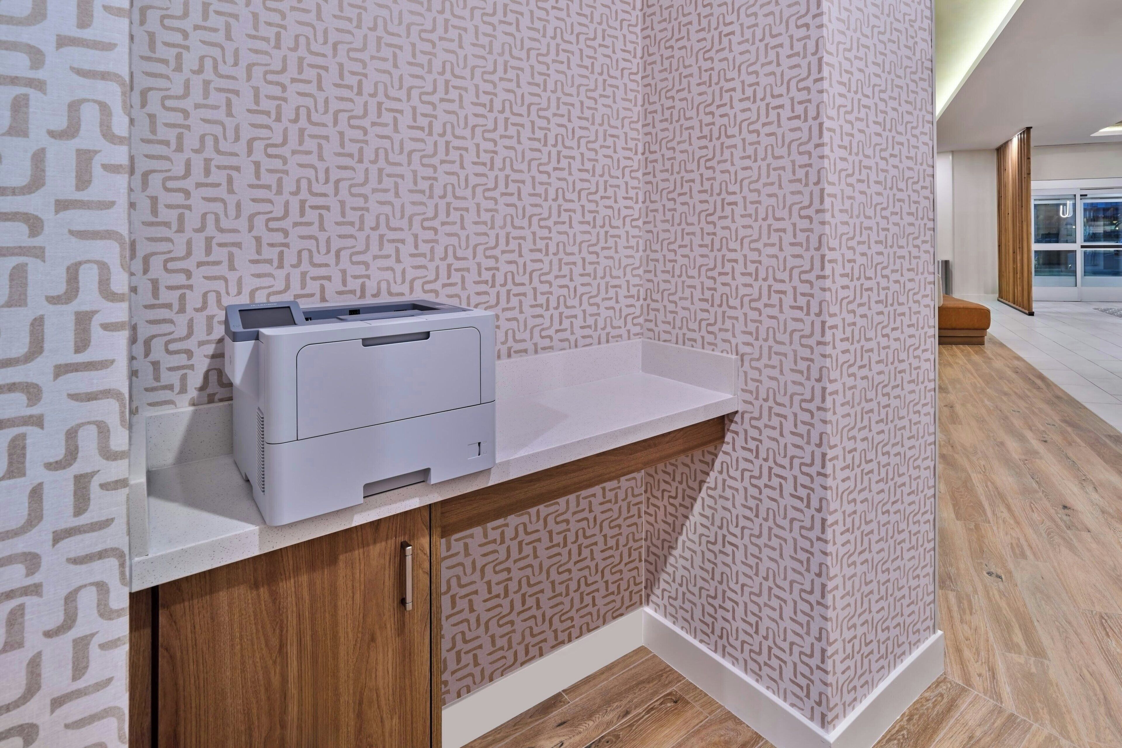 Una impresora sobre una encimera blanca, con papel tapiz estampado y suelo de madera.