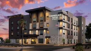 A modern hotel with a stone facade, multiple balconies, and a flag.