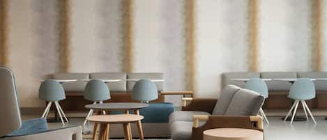 A modern lounge area with sofas, armchairs, and round tables.