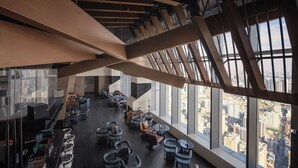 A modern interior with high ceilings, large windows, and a variety of seating arrangements.
