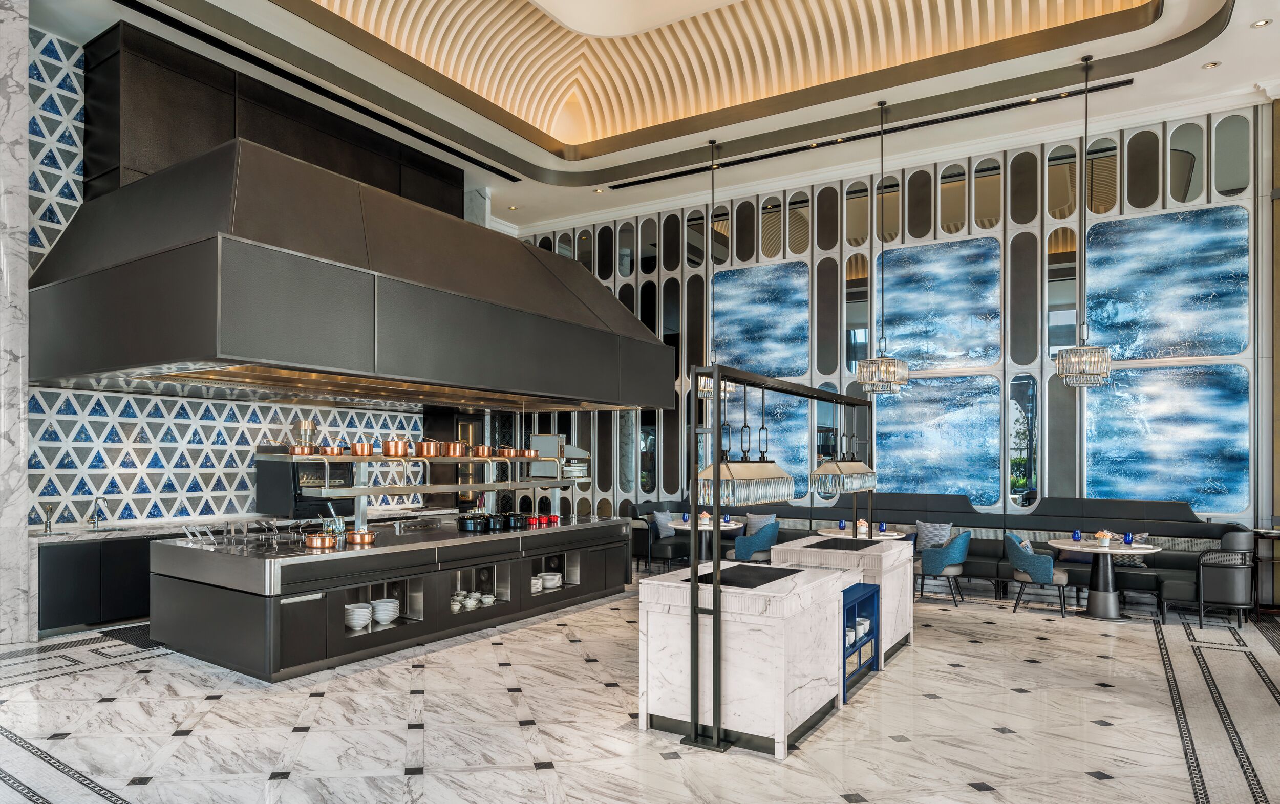 Une cuisine moderne dotée d’un grand îlot central, d’un coin bar et d’un espace détente offrant une vue sur une fresque murale abstraite aux tons bleus.