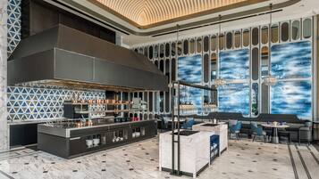 Une cuisine moderne dotée d’un grand îlot central, d’un coin bar et d’un espace détente offrant une vue sur une fresque murale abstraite aux tons bleus.