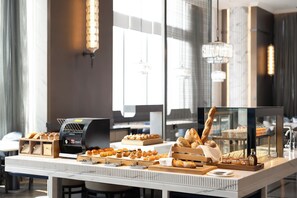 A breakfast buffet with various pastries and bread, a coffee machine, and a glass display case. - The Ritz-Carlton, Wuhan (Wuhan)