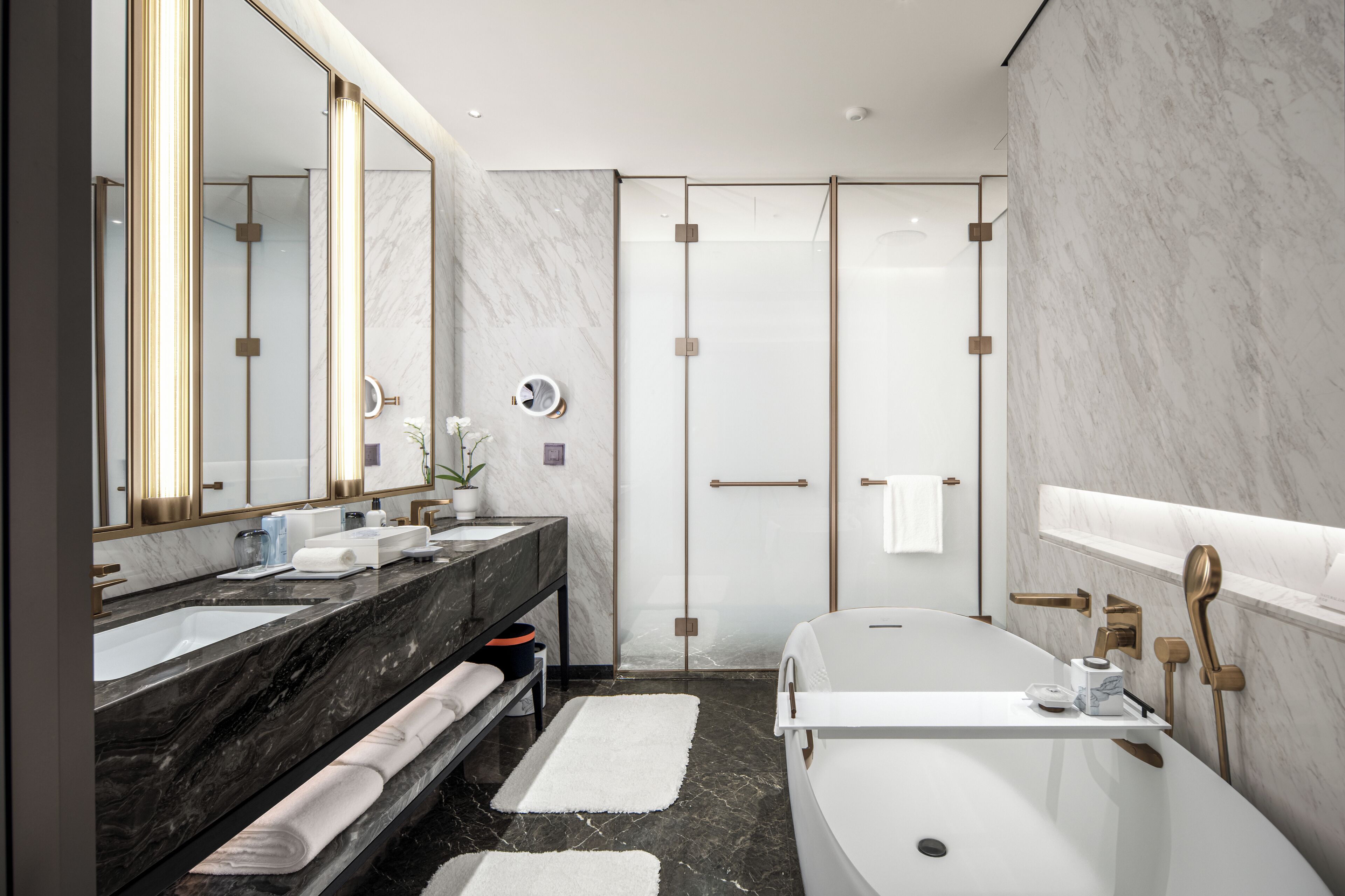A modern bathroom with a large mirror, two sinks, a bathtub, and a shower enclosure.