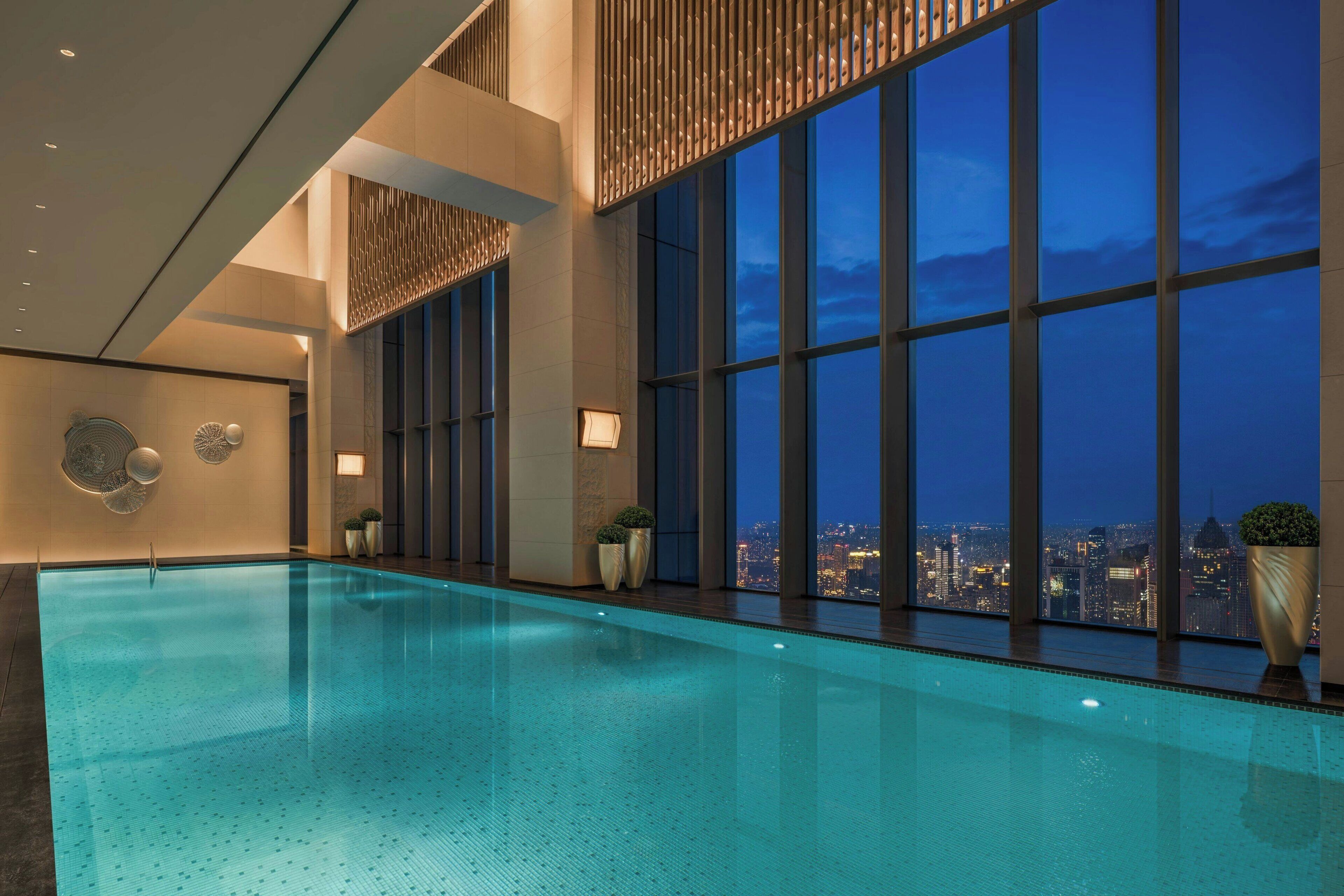 A modern indoor swimming pool with large windows offering a city view.