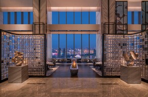 A modern interior with a city view, featuring a central seating area, a decorative sculpture, and a patterned wall. - The Ritz-Carlton, Wuhan (Wuhan)