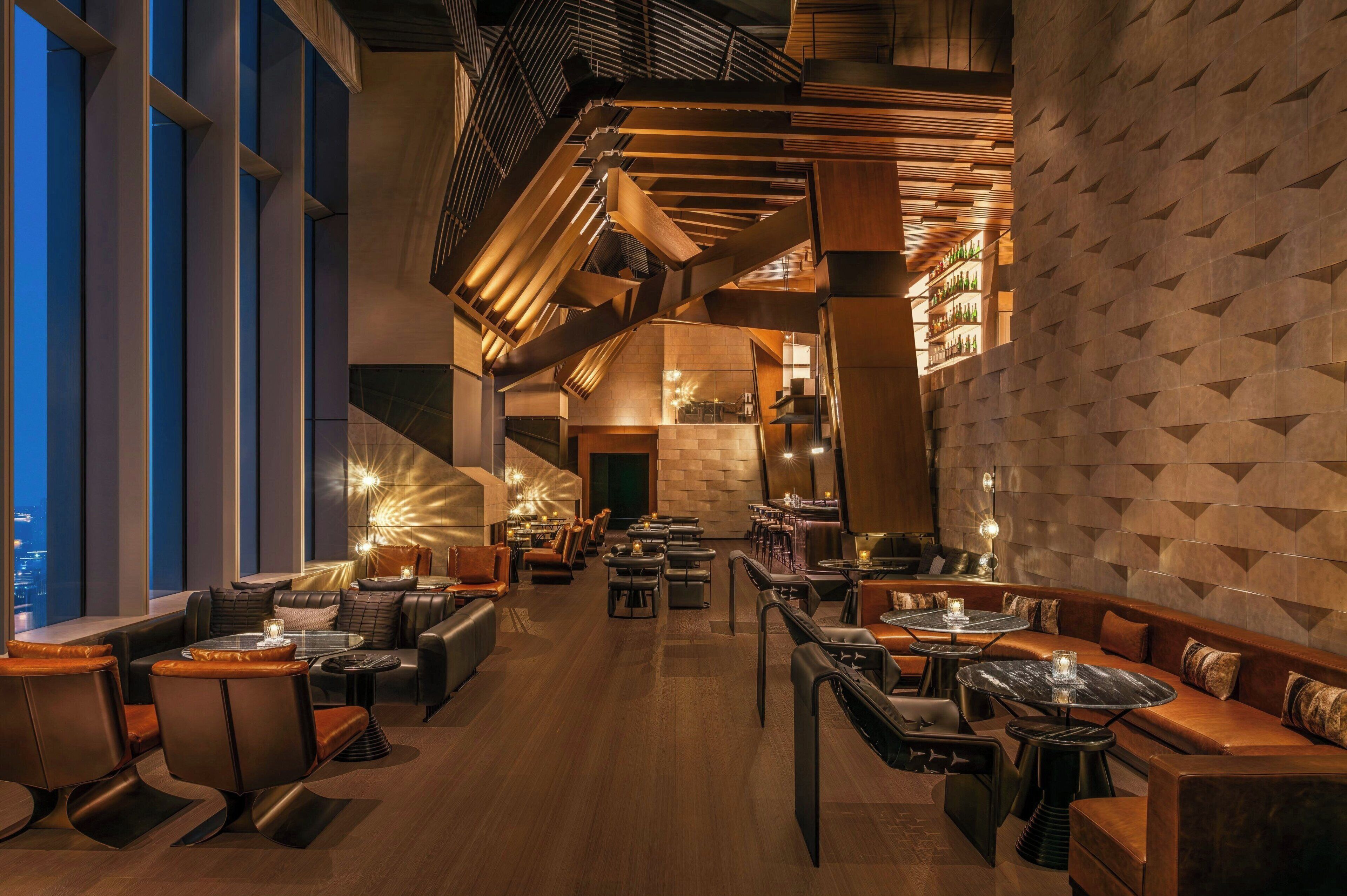 A modern interior with a staircase, seating areas, and a city view.