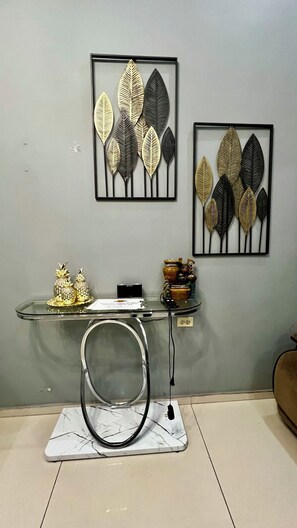 A room with a glass table displaying decorative items, a framed artwork of leaves on the wall, and a marble-patterned mat on the floor. - Casa centrica en comayagua, Bo. San blas. para 9 personas (Comayagua)