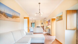 A spacious living area with a large sectional sofa, a dining area with a kitchen in the background, and artwork on the walls. - Casa Quinta de Agriboa (Ponte de Lima)