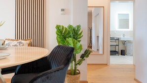 Un salon moderne avec une table ronde, des chaises noires, une grande plante verte et un mur fait de lattes de bois disposées verticalement.