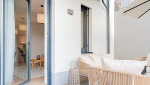 Un intérieur moderne avec des meubles en osier, une lanterne décorée et une porte en verre donnant sur une autre pièce.
