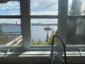 Ikkunasta avautuu näkymä järvelle, ja siellä näkyy punainen poiju sekä kauempana sijaitseva saari.