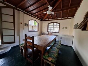 Un comedor con una mesa de madera, bancos y un ventilador de techo.