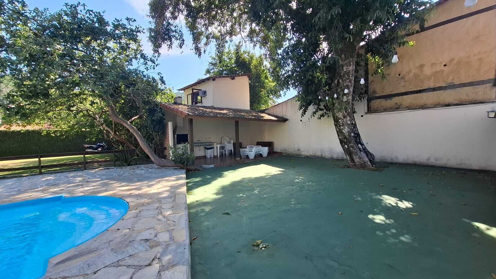 Un patio trasero con piscina, un área de patio techada y un edificio con techo de tejas.