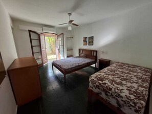 Un dormitorio con una cama, una mesita de noche de madera, un armario y un ventilador de techo.