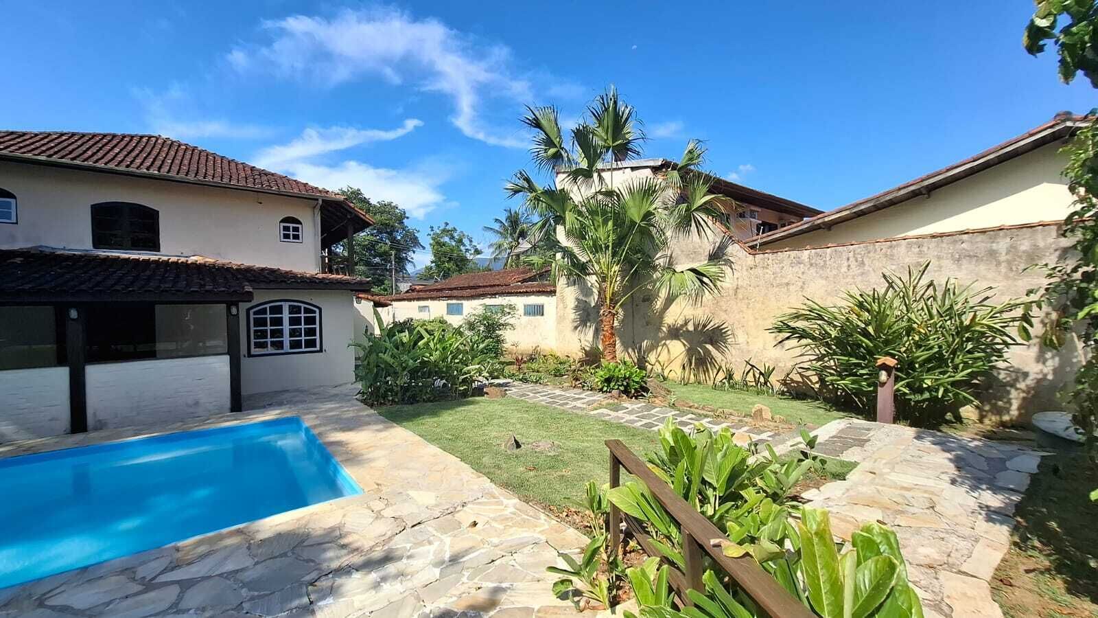 A backyard with a swimming pool, a small garden, and a house with a tiled roof.