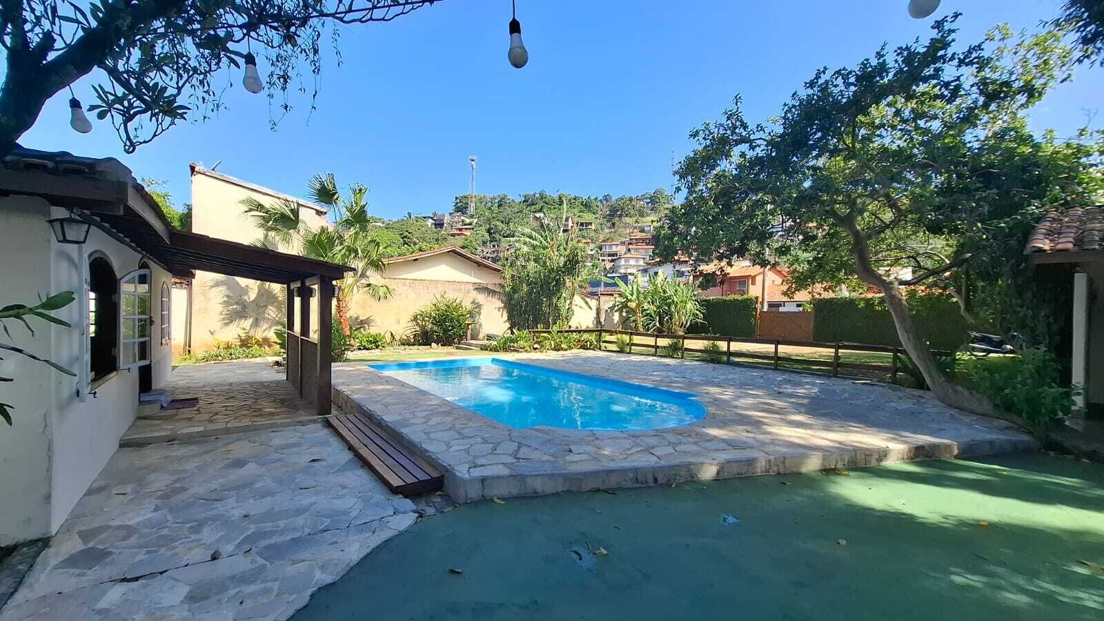Un giardino sul retro con piscina, patio in pietra e un pergolato.