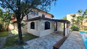 Une maison dotée d’une terrasse en pierre, d’une piscine et d’un espace extérieur couvert.