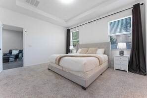 A modern bedroom with a large bed, a bedside table with a lamp, and a view of the outdoors through the window. - Comfort & Tranquility • Saint Cloud•Pool•Lake Nona (St. Cloud)