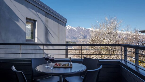 Un balcone con un tavolo apparecchiato per due persone, due bicchieri di vino e un piatto di cibo.