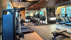 Un gimnasio con cintas de correr, máquinas de pesas y una banca.