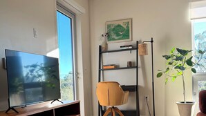 Una sala moderna con un mueble de madera para entretenimiento, una mesa de centro de vidrio y una alfombra estampada.