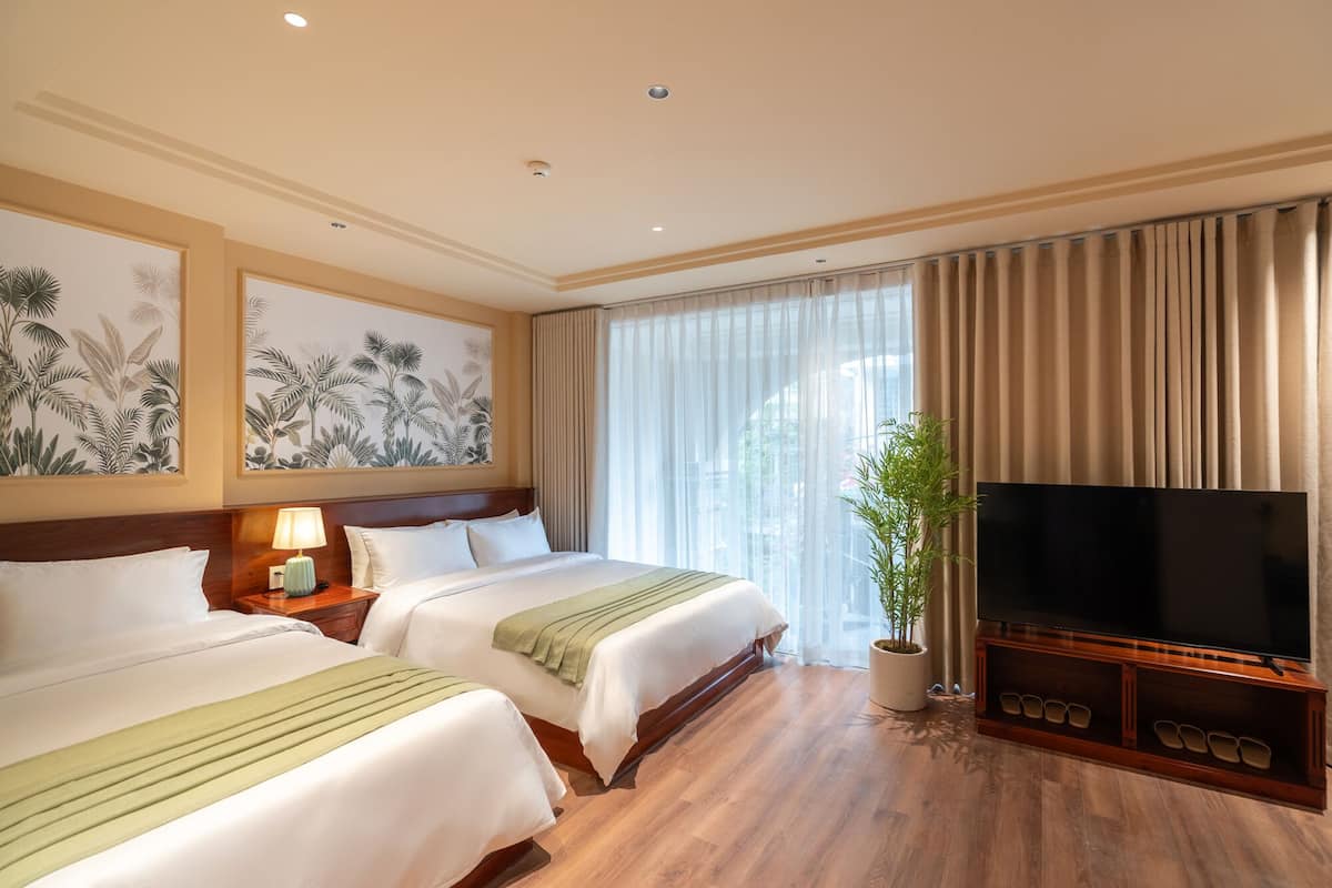Une chambre d’hôtel avec deux lits, une télévision et une grande fenêtre avec des rideaux.