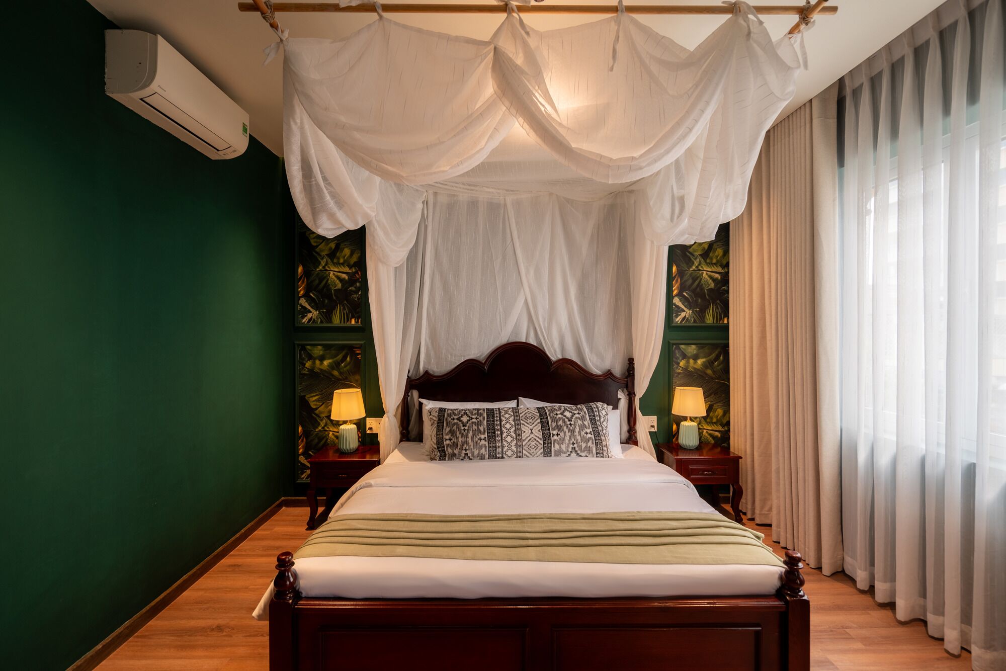 A bedroom with a canopy bed, green walls, and two bedside lamps.