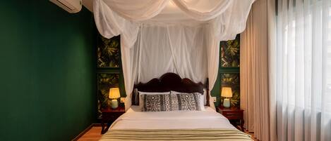 A bedroom with a canopy bed, green walls, and two bedside lamps.