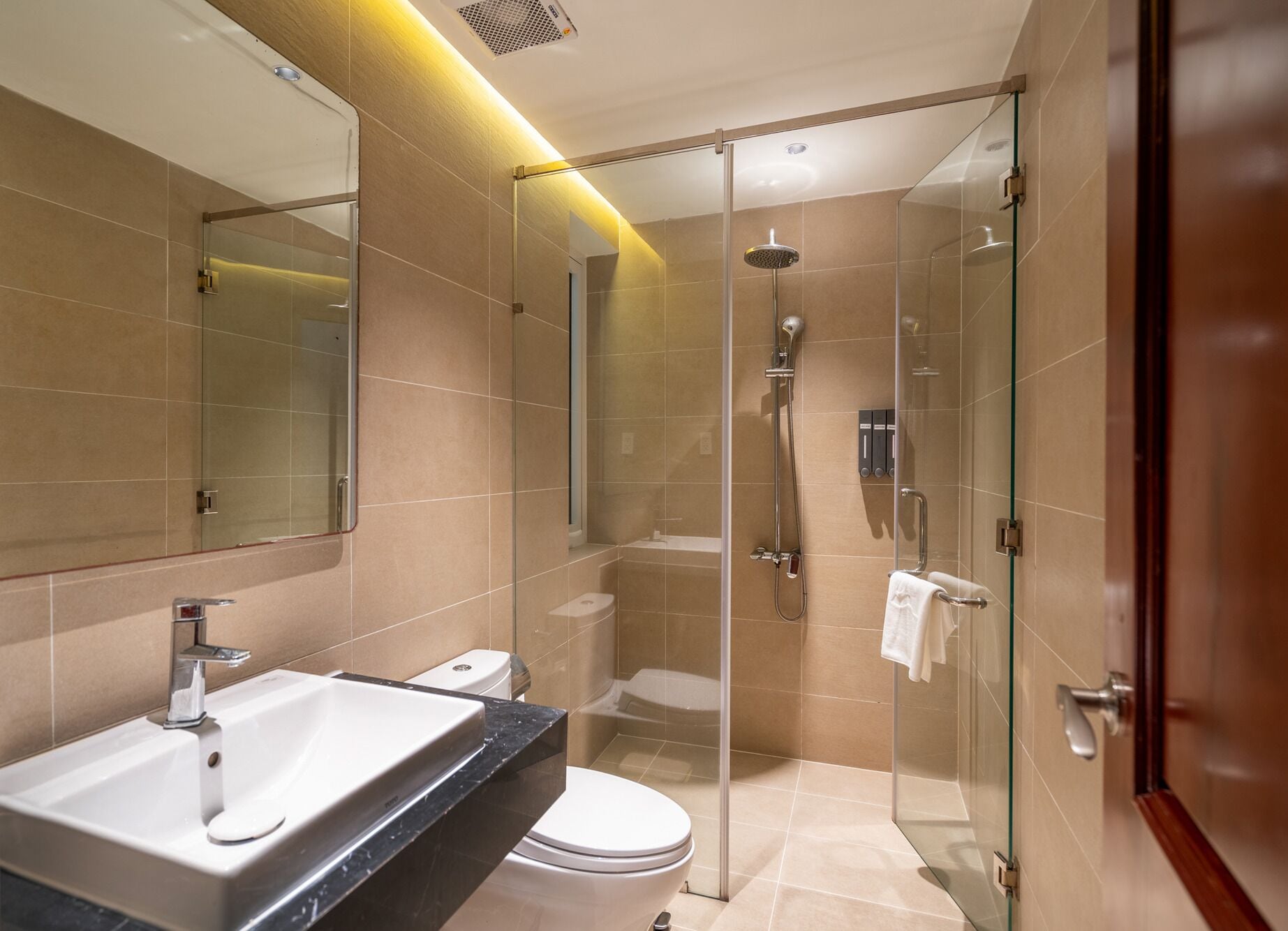 A modern bathroom with a glass-enclosed shower, a white sink, and a toilet.