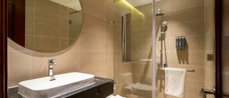 A modern bathroom with a sink, toilet, and glass-enclosed shower area.