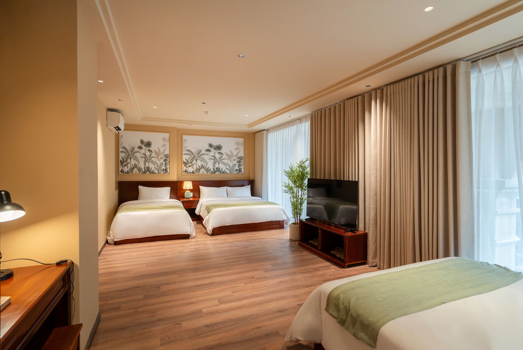 Ein Hotelzimmer mit zwei Betten, einem Fernseher und einem Schreibtisch mit Lampe.