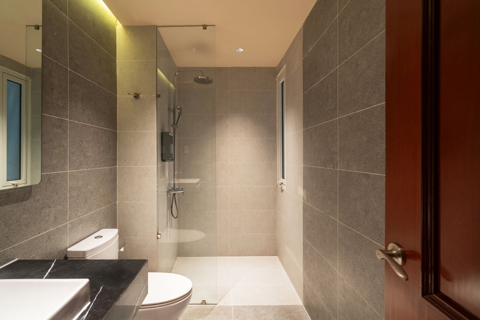 A modern bathroom with a shower, toilet, and sink.