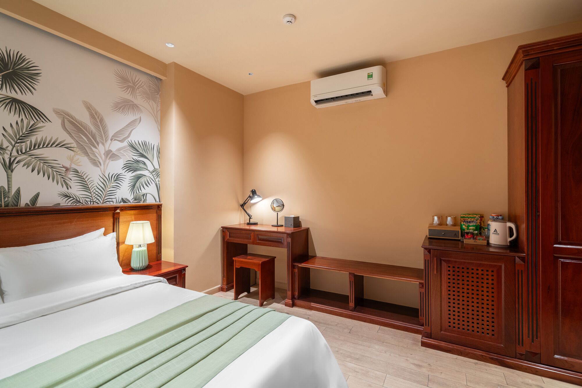 A hotel room with a bed, desk, and wardrobe.