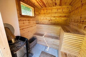 Et sauna-rum med trævægge, en bænk og en saunaovn.