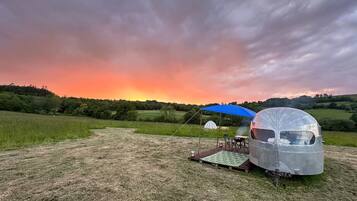 Un campeggio con un camper e una tenda sotto una volta celeste, sullo sfondo un tramonto.