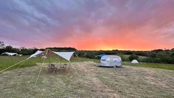 Un camping con tiendas de campaña y una caravana instalado en un campo de césped.