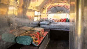 A narrow, metallic interior with a bunk bed and a bench.