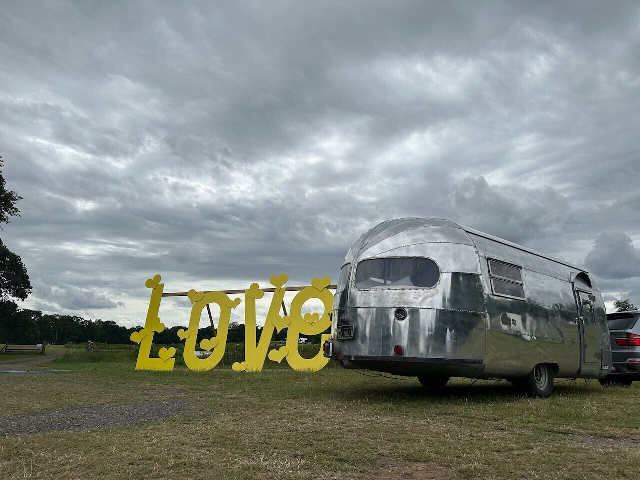 Una carreta vintage estacionada en un campo cubierto de hierba, bajo un cielo nublado.