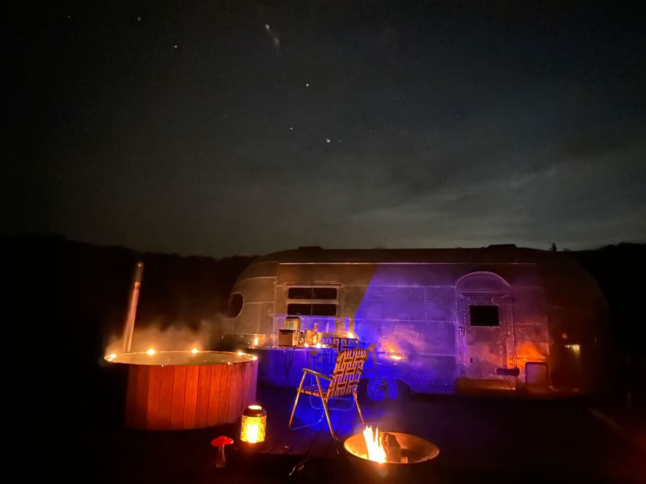 A large RV with a bar area, a fire pit, and a seating area.