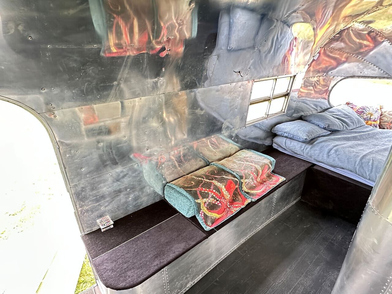 A compact, metallic interior with a bench and a bed.