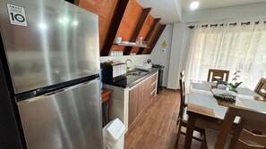Una cocina moderna con un refrigerador de acero inoxidable, armarios de madera y un comedor con mesa y sillas.