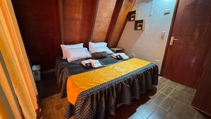 Una habitación pequeña y acogedora con una cama, una mesita de noche y una puerta.
