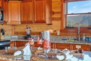 Eine Küche mit Holzausstattung, einer Arbeitsplatte aus Granit und Bergblick durch ein Fenster.