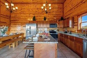 Eine geräumige Küche mit Holzschränken, einer Granit Arbeitsplatte, Edelstahlgeräten und einer großen Kochinsel.